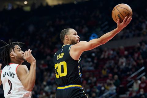 Golden State Warriors guard Stephen Curry, right, shoots in front of Portland Trail Blazers forward Trendon Watford during the first half of an NBA basketball game in Portland, Ore., Thursday, Feb. 24, 2022. (AP Photo/Craig Mitchelldyer)