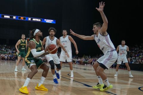 Australia's Patty Mills, left, tries to score as Serbia's Vanja Marinkovic blocks him during an exhibition basketball match between Australia and Serbia at the USA Basketball Showcase, ahead of the 2024 Paris Olympic basketball tournament, in Abu Dhabi, United Arab Emirates, Tuesday, July 16, 2024. (AP Photo/Altaf Qadri)