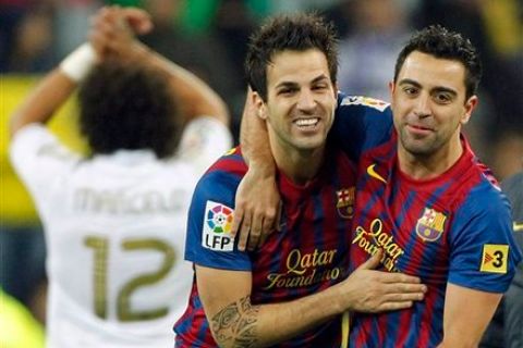 FC Barcelona's Cesc Fabregas, center, celebrates with Xavi Hernandez, right, during the Spanish La Liga soccer match against Real Madrid at the Santiago Bernabeu stadium in Madrid, Spain, Saturday, Dec. 10, 2011. (AP Photo/Andres Kudacki)