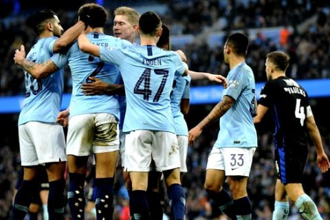 Manchester City's Riyad Mahrez , left, with teammates Kyle Walker, Phil Foden, and Kevin De Bruyne all celebrate after Rotherham's Semi Ajayi scored an own goal during the English FA Cup third round soccer match between Manchester City and Rotherham United at Etihad stadium in Manchester, England, Sunday, Jan. 6, 2019. (AP Photo/Rui Vieira)