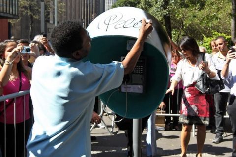 Brazilian football legend Pele autographs a phone booth at Paulista Avenue, in Sao Paulo, Brazil on May 8, 2014 as part of an advertising campaign for a telephone company. Photo: Sergio Castro/Estadao Conteudo. 