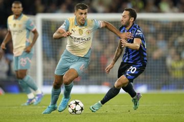 Manchester City's Rodrigo, left, runs with the ball past Inter Milan's Hakan Calhanoglu during the Champions League opening phase soccer match between Manchester City and Inter Milan at the Etihad Stadium, in Manchester, England, Wednesday, Sept. 18, 2024. (AP Photo/Dave Thompson)