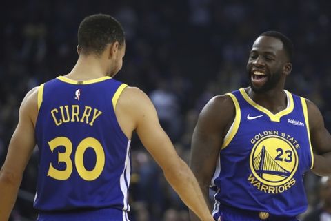 Golden State Warriors' Draymond Green, right, greets Stephen Curry (30) prior to the first half of an NBA basketball game against the Minnesota Timberwolves Monday, Dec. 10, 2018, in Oakland, Calif. The first game both have retuned to play at home since recovering from injuries. (AP Photo/Ben Margot)