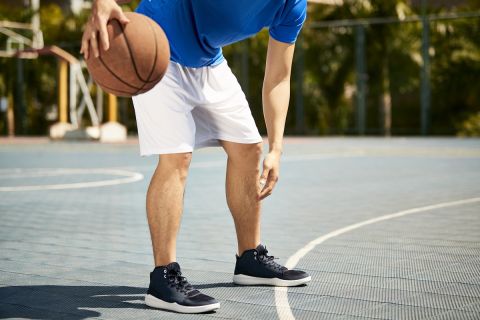 young asian male basketball player dribbling and practicing ball handling skill on court.