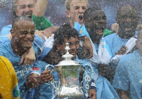 Manchester City's Argentinian footballer Carlos Tevez (C) celebrates with the FA Cup after beating Stoke 1-0 during the FA Cup final football match between Manchester City and Stoke City at Wembley Stadium in London, on May 14, 2011. AFP PHOTO / ADRIAN DENNIS
NOT FOR MARKETING OR ADVERTISING USE/RESTRICTED TO EDITORIAL USE (Photo credit should read ADRIAN DENNIS/AFP/Getty Images)