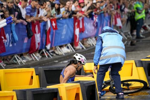 Manami Iijima, of Guam, is helped by staff after crashing during the bike leg of the women's individual triathlon competition at the 2024 Summer Olympics, Wednesday, July 31, 2024, in Paris, France. (AP Photo/David Goldman)