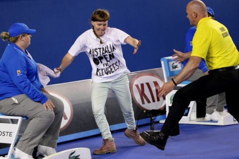 A political protester, center, is chased by a guard before he was taken away from Rod Laver Arena during the men's singles final between Andy Murray of Britain and Novak Djokovic of Serbia at the Australian Open tennis championship in Melbourne, Australia, Sunday, Feb. 1, 2015. (AP Photo/Rob Griffith) ORG XMIT: MEL203