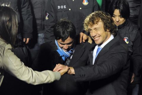 Uruguay's captain Diego Lugano (R) shakes hands with a supporter at the Centenario stadium in Montevideo on July 25, 2011, after winning the Copa America tournament. Uruguay defeated Paraguay 3-0 on July 24 to win a record 15th Copa America with striker Diego Forlan grabbing two goals to take his international tally to 31 and complete an incredible family story. AFP PHOTO / PABLO PORCIUNCULA (Photo credit should read PABLO PORCIUNCULA/AFP/Getty Images)