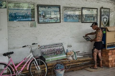 TO GO WITH AFP STORY by Javier Tovar
Brazilian football club Botafogo fan Delneri Martins Viana, a 69-year-old retired soldier, looks at pictures of players of the club at his home in Rio de Janeiro, Brazil, on January 18, 2014. Delneri has 83 tattoos on his body dedicated to Botafogo and describes himself as the club's biggest fan.   AFP PHOTO / YASUYOSHI CHIBA