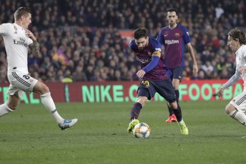 Real midfielder Toni Kroos, left, and Real midfielder Luka Modric, right, run to stop Barcelona forward Lionel Messi, center, during the Copa del Rey semifinal first leg soccer match between FC Barcelona and Real Madrid at the Camp Nou stadium in Barcelona, Spain, Wednesday Feb. 6, 2019. (AP Photo/Emilio Morenatti)