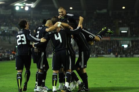 SANTANDER, SPAIN - MARCH 06:  Karim Benzema (R) of Real Madrid jumps on top of his teammates as they celebrate Emanuel Abadayour's opening goal during the la Liga match between Racing Santander and Real Madrid at El Sardinero stadium on March 6, 2011 in Santander, Spain.  (Photo by Jasper Juinen/Getty Images)