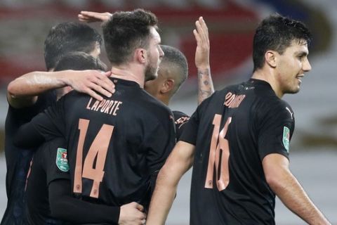 Manchester City's Aymeric Laporte is congratulated by teammates after scoring his team's fourth goal during the English League Cup quarterfinal soccer match between Arsenal and Manchester City at Emirates Stadium, London, Tuesday, Dec. 22, 2020. (AP Photo/Frank Augstein)