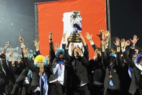 Uruguay's captain Diego Lugano (C) holds the Copa America trophy as he celebrates his team's victory with his teammates at the Centenario stadium in Montevideo on July 25, 2011. Uruguay defeated Paraguay 3-0 on July 24 to win a record 15th Copa America with striker Diego Forlan grabbing two goals to take his international tally to 31 and complete an incredible family story. AFP PHOTO / PABLO PORCIUNCULA (Photo credit should read PABLO PORCIUNCULA/AFP/Getty Images)