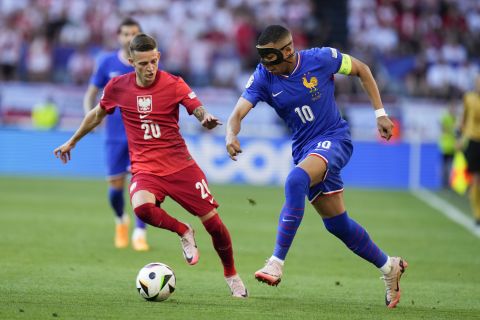 Kylian Mbappe of France, right, passes the ball past Poland's Sebastian Szymanski during a Group D match between France and Poland at the Euro 2024 soccer tournament in Dortmund, Germany, Tuesday, June 25, 2024. (AP Photo/Hassan Ammar)