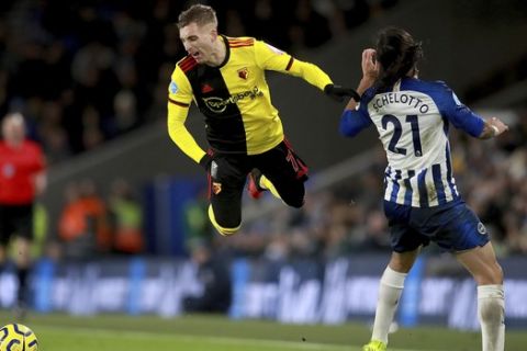 Watford's Gerard Deulofeu takes a tumble after a challenge from Brighton and Hove Albion's Ezequiel Schelotto, right, during the English Premier League soccer match at the AMEX Stadium, Brighton, England, Saturday Feb. 8, 2020. (Adam Davy/PA via AP)