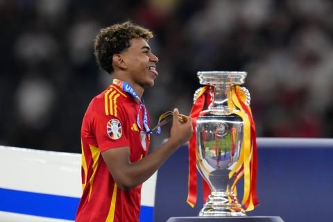 Spain's Lamine Yamal smiles with his medal next to the trophy after winning the final match between Spain and England at the Euro 2024 soccer tournament in Berlin, Germany, Sunday, July 14, 2024. Spain won 2-1. (AP Photo/Manu Fernandez)