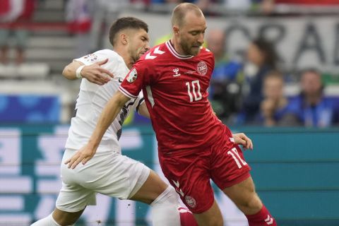 Denmark's Christian Eriksen, right, is tackled Slovenia's Erik Janza during a Group C match between Slovenia and Denmark at the Euro 2024 soccer tournament in Stuttgart, Germany, Sunday, June 16, 2024. (AP Photo/Matthias Schrader)