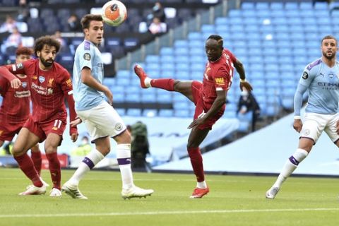 Liverpool's Sadio Mane, second right, watches as he heads the ball during the English Premier League soccer match between Manchester City and Liverpool at Etihad Stadium in Manchester, England, Thursday, July 2, 2020. (AP Photo/Peter Powell,Pool)