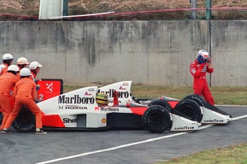 SUZAKA, JAPAN:  Ayrton Senna of Brazil is given a push from circuit marshals for a restart while his teammate and bitter rival Alain Prost of France leaves his car to abandon the race after the two collided in a chicane during the Japan Formula One Grand Prix in Suzuka 22 October 1989. Senna received the chequered flag but was later disqualified after being accused of receiving an illegal push from marshals and of taking a short cut through the chicane. AFP PHOTO TOSHIFUMI KITAMURA (Photo credit should read TOSHIFUMI KITAMURA/AFP/Getty Images)