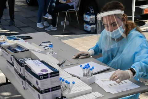 Γιατρός του ΕΟΔΥ μαζεύει τα δείγματα από τεστ κορονοϊού που γίνονται στο κέντρο