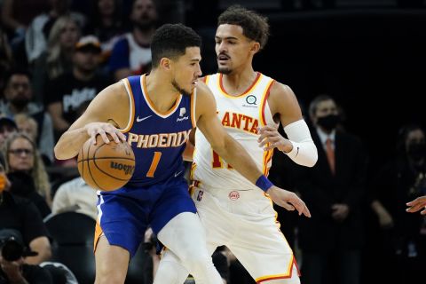 Phoenix Suns guard Devin Booker (1) backs down Atlanta Hawks guard Trae Young during the first half of an NBA basketball game, Saturday, Nov. 6, 2021, in Phoenix. (AP Photo/Matt York)