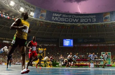 Jamaica's Usain Bolt (L) wins the100 metres final at the 2013 IAAF World Championships at the Luzhniki stadium in Moscow on August 11, 2013 while a lightning strikes in the sky. Bolt timed a season's best 9.77 seconds, with American Justin Gatlin claiming silver in 9.85sec and Nesta Carter, also of Jamaica, taking bronze in 9.95sec. 
 AFP PHOTO / OLIVIER MORIN        (Photo credit should read OLIVIER MORIN/AFP/Getty Images)