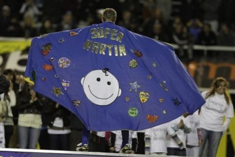 Boca Juniors' Martin Palermo shows off to fans a poncho made by children from the soccer club after he played his last game at La Bombonera stadium, an Argentine league soccer match with Banfield, in Buenos Aires, Argentina, Sunday June 12, 2011. Palermo is retiring from professional soccer. (AP Photo/Eduardo Di Baia)