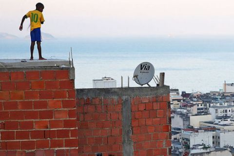 RIO DE JANEIRO, BRAZIL - JULY 04:  A boy wears a Neymar jersey as he flies a kite from a rooftop in the Cantagalo favela at the start of the Brazil-Colombia match on July 4, 2014 in Rio de Janeiro, Brazil. Kite flying and soccer are both popular pastimes in Rio's favelas.  (Photo by Mario Tama/Getty Images)