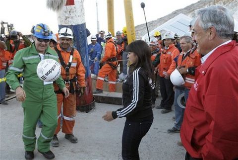 In this photo released by the Chilean Presidential Press Office, miner Franklin Lobo, left, a former professional soccer player, plays with a soccer ball as his daughter Carolina, center, and Chile's President Sebastian Pinera, right, looks on after he was rescued from the collapsed San Jose gold and copper mine where he had been trapped with 32 other miners for over two months near Copiapo, Chile, Wednesday Oct. 13, 2010.   (AP Photo/Alex Ibanez, Chilean Presidential Press Office)