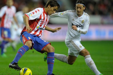 Sporting Gijon's Argentinian forward Oscar Trejo (L) vies with Real Madrid's German midfielder Mesut Ozil (R) during their Spanish first league football match Sporting Gijon vs Real Madrid at El Molinon Stadium in Gijon, on December 3, 2011. AFP PHOTO / MIGUEL RIOPA (Photo credit should read MIGUEL RIOPA/AFP/Getty Images)