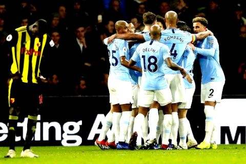 Manchester City's Leroy Sane, covered by his teammates, celebrates after scoring his side's opening goal during the English Premier League soccer match between Watford and Manchester City at Vicarage Road stadium in Watford, England, Tuesday, Dec. 4, 2018. (AP Photo/Frank Augstein)