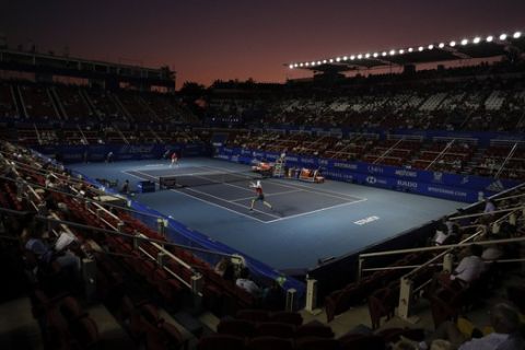 John Isner of the U.S., front, returns a ball in his semifinal match against Taylor Fritz of the U.S. at the Mexican Tennis Open in Acapulco, Mexico, Friday, Feb. 28, 2020.(AP Photo/Rebecca Blackwell)