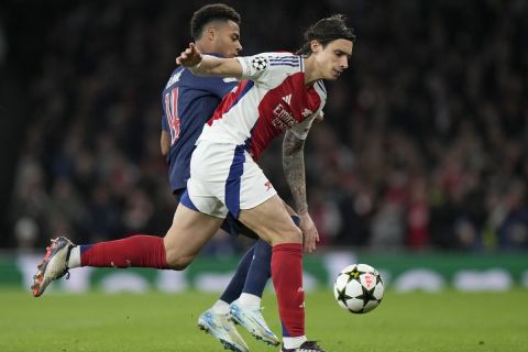 Arsenal's Riccardo Calafiori vies for the ball with PSG's Desire Doue, left, during a Champions League opening phase soccer match between Arsenal FC and Paris Saint-Germain at Arsenal stadium in London, England, Tuesday, Oct. 1, 2024. (AP Photo/Alastair Grant)