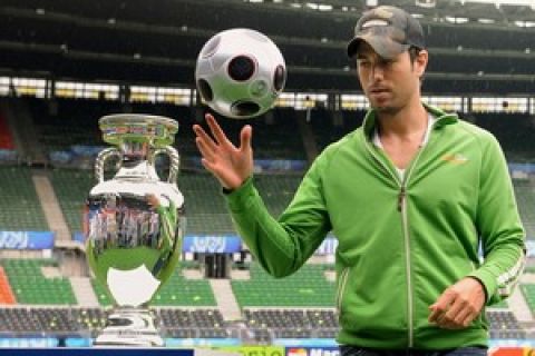 Spanish singer Enrique Iglesias plays with a ball next the Euro Trophy at Ernst Happel stadium in Vienna on June 27, 2008. Enrique Iglesias will perform the official UEFA EURO 2008 song "Can you hear me" on 29 June 2008 at the final ceremony before the kick-off of the final  AFP PHOTO / ALBERTO PIZZOLI (Photo credit should read ALBERTO PIZZOLI/AFP/Getty Images)