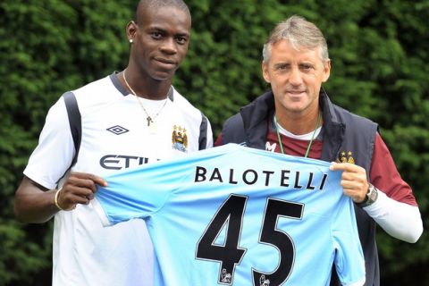 Italian footballer Mario Balotelli (L) poses for photographers with Manchester City manager Roberto Mancini at their Carrington training complex in Manchester, north-west England, on August 17, 2010. Balotelli agreed a five-year contract with the Premier League club and is City's fifth big-money signing since the end of last season, taking their spending to over 100 million pounds (121 million euros) after the arrivals of Jerome Boateng, David Silva, Yaya Toure and Aleksandar Kolarov. AFP PHOTO/ANDREW YATES    FOR  EDITORIAL USE Additional licence required for any commercial/promotional use or use on TV or internet (except identical online version of newspaper) of Premier League/Football League photos. Tel DataCo +44 207 2981656. Do not alter/modify photo (Photo credit should read ANDREW YATES/AFP/Getty Images)