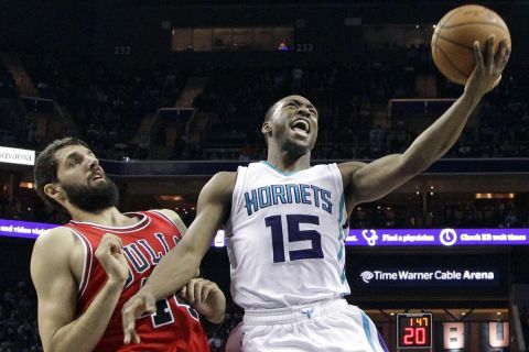 Charlotte Hornets' Kemba Walker, right, drives past Chicago Bulls' Nikola Mirotic, left, during the second half of an NBA basketball game in Charlotte, N.C., Wednesday, Dec. 3, 2014. The Bulls won 102-95. (AP Photo/Chuck Burton)