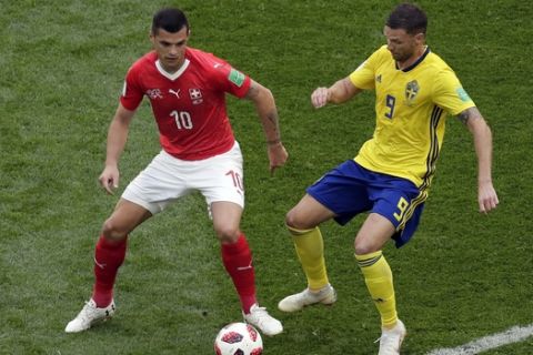 Switzerland's Granit Xhaka, left, duels for the ball with Sweden's Marcus Berg during the round of 16 match between Switzerland and Sweden at the 2018 soccer World Cup in the St. Petersburg Stadium, in St. Petersburg, Russia, Tuesday, July 3, 2018. (AP Photo/Dmitri Lovetsky)