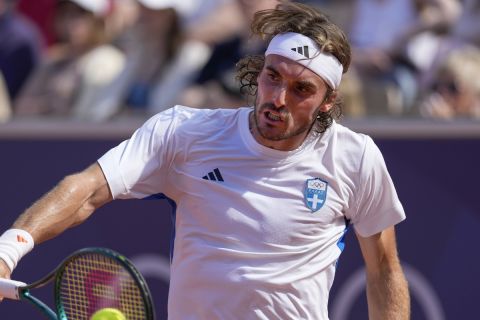 Stefanos Tsitsipas of Greece hits a backhand shot to Zizou Bergs of Belgium during the men's singles tennis competition, at the 2024 Summer Olympics, Sunday, July 28, 2024, in Paris, France. (AP Photo/Andy Wong)