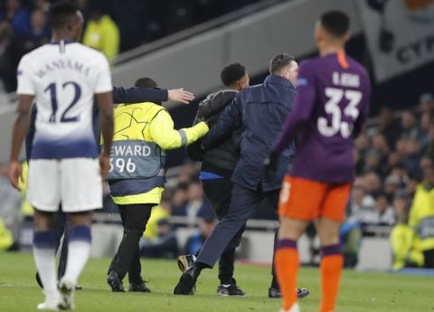 A spectators is escorted by steward after he gets into the field of play during the Champions League, round of 8, first-leg soccer match between Tottenham Hotspur and Manchester City at the Tottenham Hotspur stadium in London, Tuesday, April 9, 2019. (AP Photo/Frank Augstein)