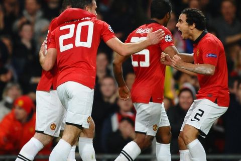 MANCHESTER, ENGLAND - MARCH 19:  Robin van Persie of Manchester United celebrates scoring the second goal with his team-mates during the UEFA Champions League Round of 16 second round match between Manchester United and Olympiacos FC at Old Trafford on March 19, 2014 in Manchester, England.  (Photo by Laurence Griffiths/Getty Images)