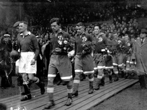 Moscow Dynamo F.C. turned out their best team to-day against Chelsea at Stamford Bridge for the first match of their English tour. A huge crowd, including many Russians, welcomed the visitors. People of several countries had brought tickets to honour the men who had helped defeat Germany in the Red Army factories. The Dynamos share of the heavy gate will be donated to charities by the F.A. as directed by the Russians. The Stalingrad fund has high place. Picture shows Harris, Chelsea captain, and Semichastny, Dynamo captain, leading their teams into the field. The Russians carry bouquets of red and white flowers which they later presented to the British team. November 13th 1945.