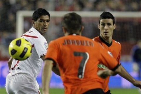 Sevilla's Renato Dirnei from Brazil, left, and Valencia's Aritz Aduriz, right, vie for the ball during their La Liga soccer match at the Ramon Sanchez Pizjuan stadium,  in Seville, Monday, Nov. 8, 2010. (AP Photo/Angel Fernandez)