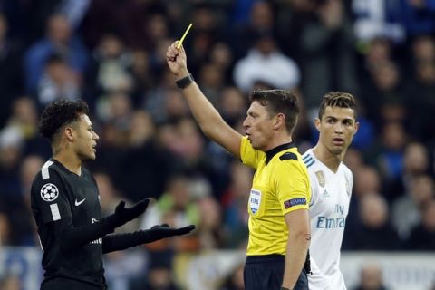 PSG's Neymar, left, reacts after getting a yellow card from referee Gianluca Rocchi of Italy while Real Madrid's Cristiano Ronaldo looks on during a Champions League Round of 16 first leg soccer match between Real Madrid and Paris Saint Germain at the Santiago Bernabeu stadium in Madrid, Spain, Wednesday, Feb. 14, 2018. (AP Photo/Francisco Seco)