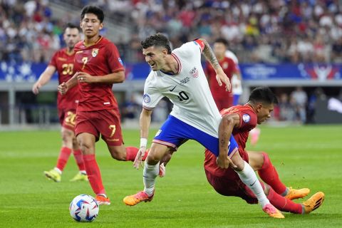 Christian Pulisic of the United States is grabbed by Bolivia's Hector Cuellar as they chase the ball during a Copa America Group C soccer match in Arlington, Texas, Sunday, June 23, 2024. (AP Photo/Julio Cortez)