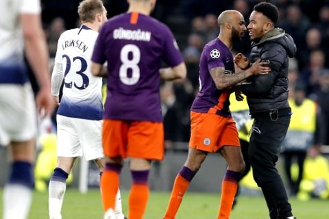 A spectators is blocked by players as he runner into the field of play during the Champions League, round of 8, first-leg soccer match between Tottenham Hotspur and Manchester City at the Tottenham Hotspur stadium in London, Tuesday, April 9, 2019. (AP Photo/Frank Augstein)