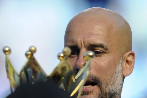 Manchester City manager Josep Guardiola looks at the English Premier League trophy after the soccer match between Manchester City and Huddersfield Town at Etihad stadium in Manchester, England, Sunday, May 6, 2018. (AP Photo/Rui Vieira)