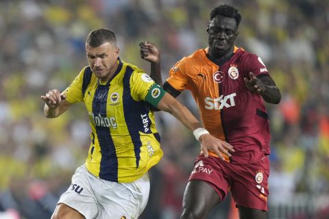 CORRECTS SPELLING OF PLAYER'S NAME - Fenerbahce's Edin Dzeko, left, fights for the ball with Galatasaray's Davinson Sanchez during the Turkish Super Lig soccer match between Fenerbahce and Galatasaray at the Sukru Saracoglu in Istanbul, Turkey, Saturday, Sept. 21, 2024. Galatasaray won 3-1. (AP Photo/Francisco Seco)