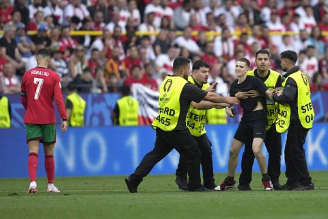 Stewards catch a pitch invader that ran to Portugal's Cristiano Ronaldo during a Group F match between Turkey and Portugal at the Euro 2024 soccer tournament in Dortmund, Germany, Saturday, June 22, 2024. (AP Photo/Darko Vojinovic)