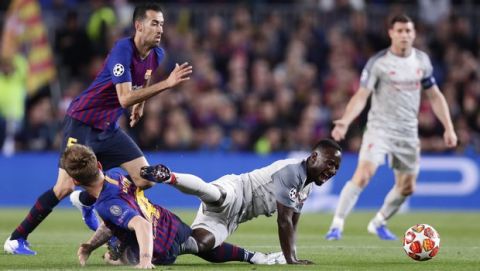 Liverpool's Naby Keita, falling, is tackled by Barcelona's Ivan Rakitic, down left, during the Champions League semifinal first leg soccer match between FC Barcelona and Liverpool at the Camp Nou stadium in Barcelona, Spain, Wednesday, May 1, 2019. Keita sustained an injury and was substituted following the tackle, and is out for at least two months with a thigh injury. (AP Photo/Manu Fernandez)