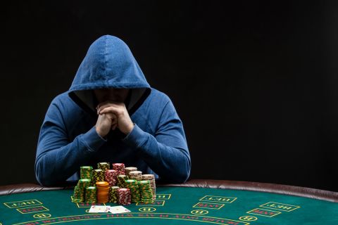 Poker player sitting at a poker table with chips table trying to hide his expressions and looking at combination of two aces. Closeup